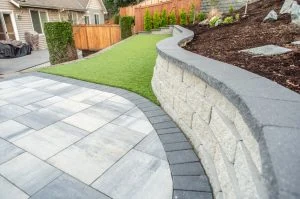 Curved retaining wall beside a light-coloured paver patio.
