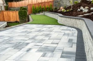 Paver patio with artificial turf and a curved retaining wall.