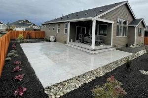 Completed light-coloured porcelain paver patio behind a home.