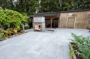 Outdoor fireplace and paved entertaining area beside a garden.