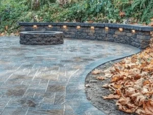 Curved paver patio and low retaining wall in a wooded garden.