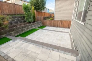 Artificial turf and paver installation beside a residential patio.