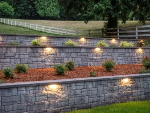 Long illuminated retaining wall across a landscaped property.