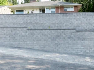 Large grey retaining wall beside a residential property.
