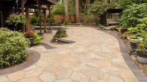 Curved stone paver patio with built-in seating in a wooded garden.