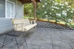Paver patio with built-in seating in a wooded backyard.