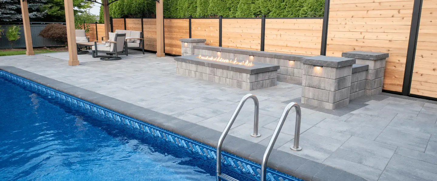Completed poolside paver patio with a fire feature and outdoor seating.